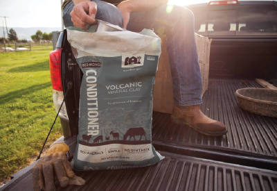 Farmer scooping bentonite conditioner in the bed of a truck